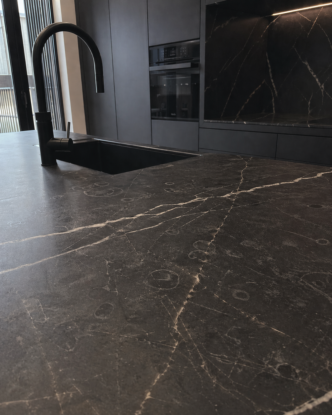 Honed black stone countertop in a dark kitchen