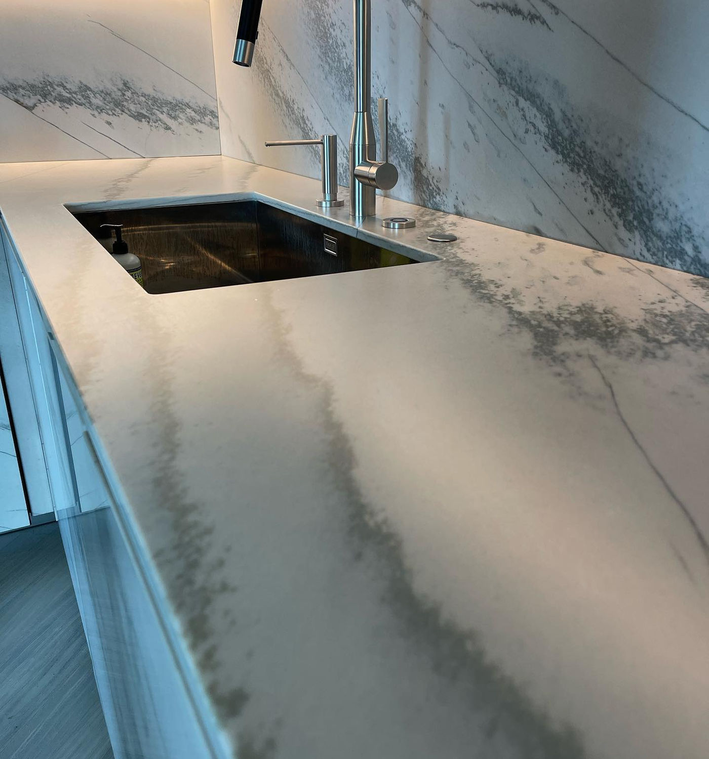 Sink run beside a full-height slab backsplash. Honed Marble with StoneGuard Satin film in Chappaqua, NY